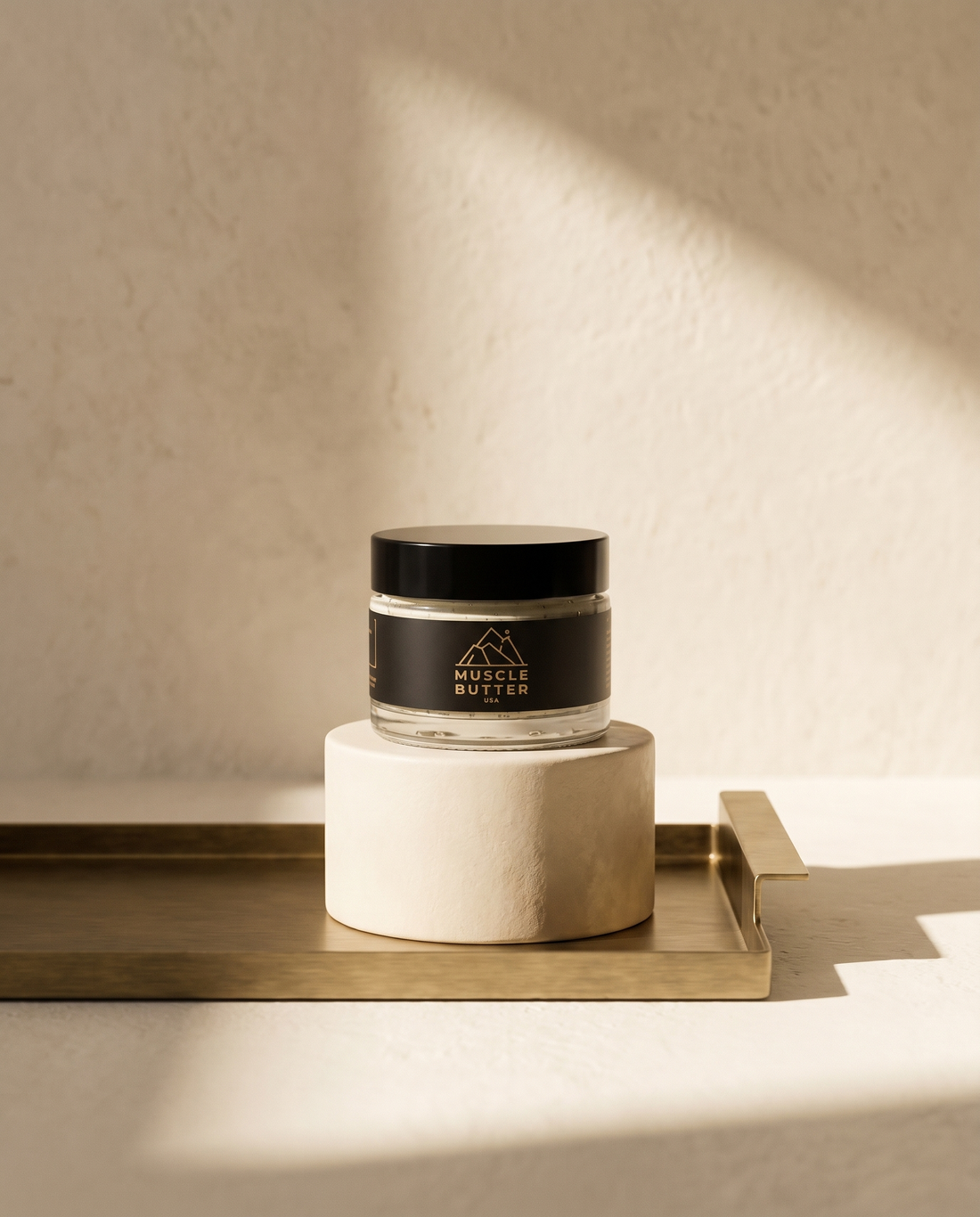 Muscle Butter USA recovery balm jar on a bone plaster pedestal and brushed brass tray