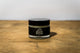 Muscle Butter USA 30ml arnica recovery balm jar with black lid on wooden surface